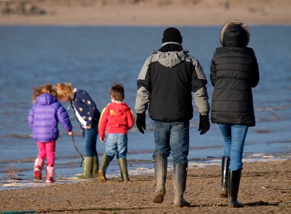 Family playing at the seaside in winter, Instow, Devon, UK. (Photo by: Education Images/Universal Images Group via Getty Images)
