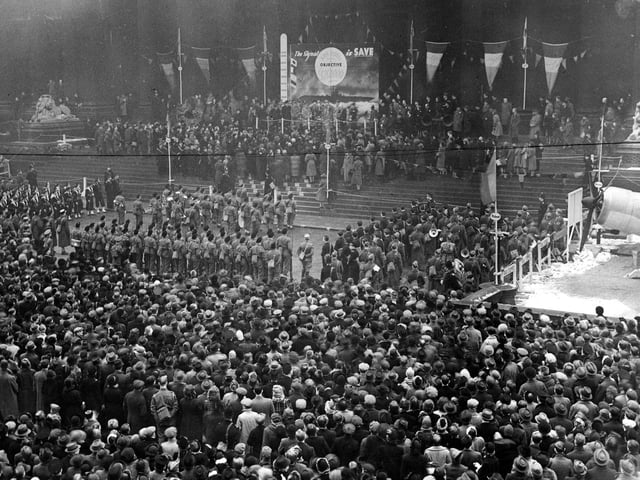 Dense crowds outside Leeds Town Hall, in front of the steps are ranked servicemen and women. On the platform is General De Gaulle, who had been invited to make a speech and move the target indicator.