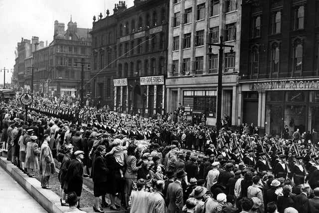 Mass crowds line The Headrow, watching a march past of sailors and WRENS during the Ark Royal Parade.