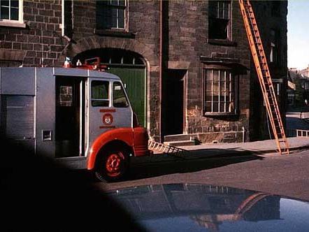 The Herb Shop in the Market Place was the scene of a fire in 1967. The fire engine has been summoned and ladders are in use. The new fire station was opened in 1958 at the end of Victoria Street and Walton Road.