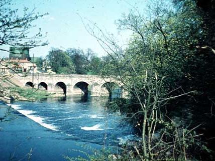 The River Wharfe looking from the top of the weir towards Wetherby Bridge. Taken in the summer of 1962, the image shows gasometers in the background.