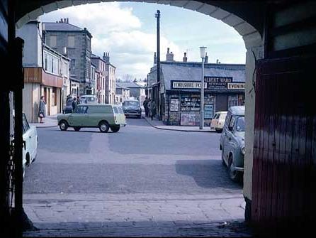 1965 and in view is the Market Place through the arched coach entrance of the Three Legs Inn. One the right is Albert Ward's Newsagents with advertising for the Yorkshire Post and your Yorkshire Evening Post.