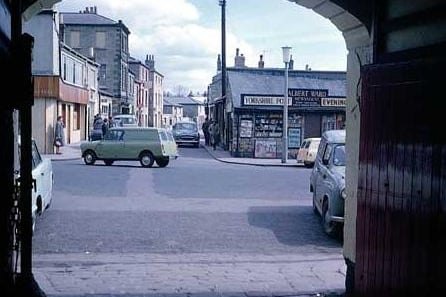 1965 and in view is the Market Place through the arched coach entrance of the Three Legs Inn. One the right is Albert Ward's Newsagents with advertising for the Yorkshire Post and your Yorkshire Evening Post.