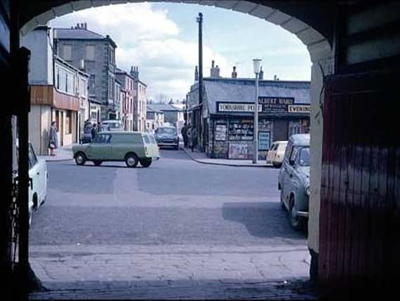 1965 and in view is the Market Place through the arched coach entrance of the Three Legs Inn. One the right is Albert Ward's Newsagents with advertising for the Yorkshire Post and your Yorkshire Evening Post.