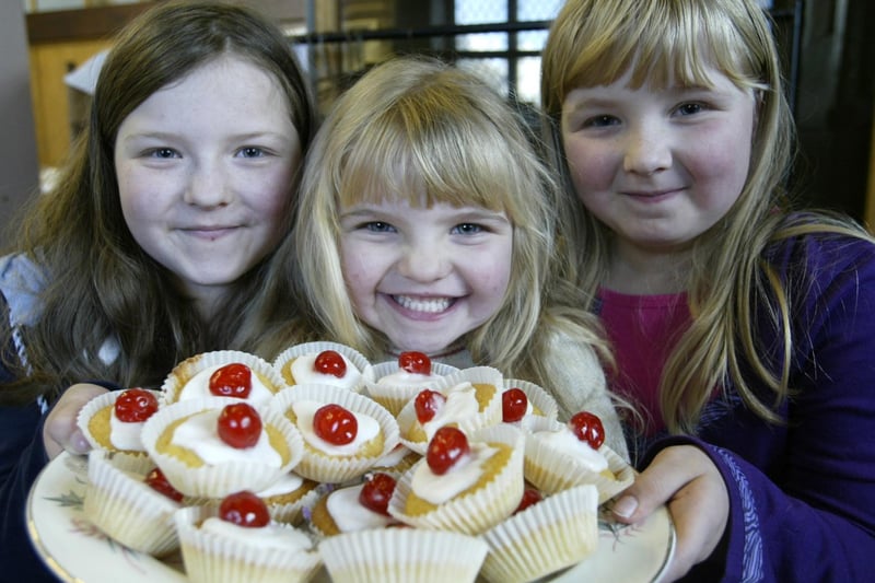 Sisters Georgia nine, Holly four and Ellen seven Taylor with cherry buns at the St Thomas Church, Claremount, table top sale.