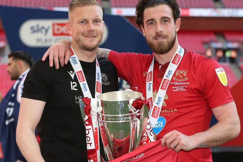 Morecambe's Mark Halstead and Cole Stockton with the trophy and a number 34 shirt as a tribute to Christian Mbulu (Photo: Rob Newell/CameraSport)