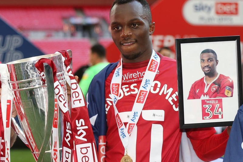Morecambe's Carlos Mendes Gomes with the trophy and a photo of Christian Mbulu (Photo: Rob Newell/CameraSport)