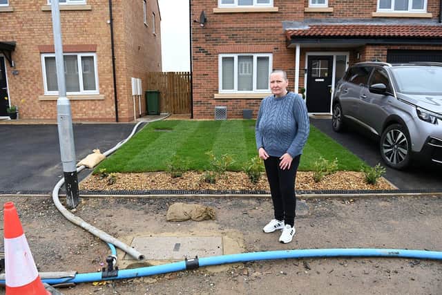 Angie Williams outside her Hartwell Park home with the temporary water supply pipes. Picture by FRANK REID