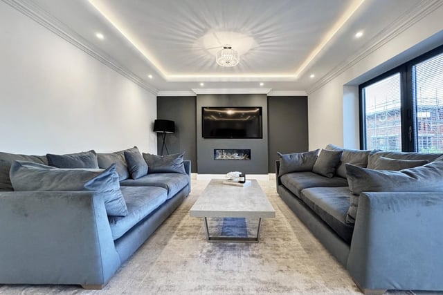 This home has a large, open plan snug, dining area, kitchen and garden room at the back of the property, perfect for entertaining guests. The snug, as pictured, has a media wall and recessed modern fire as well as ceiling spotlights.