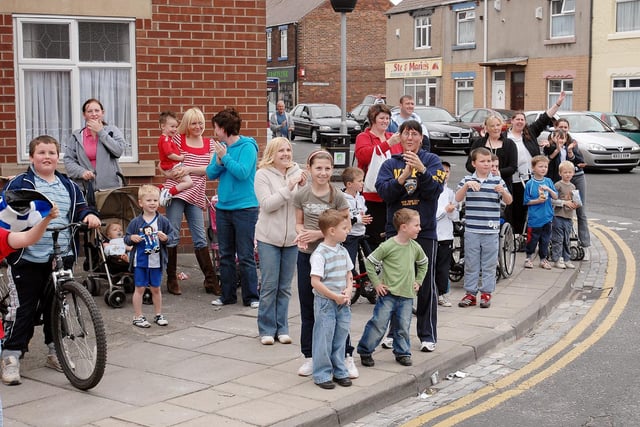 Onlookers wait on a street corner for the Hartlepool United bus to pass following the club's 2007 promotion from League Two.