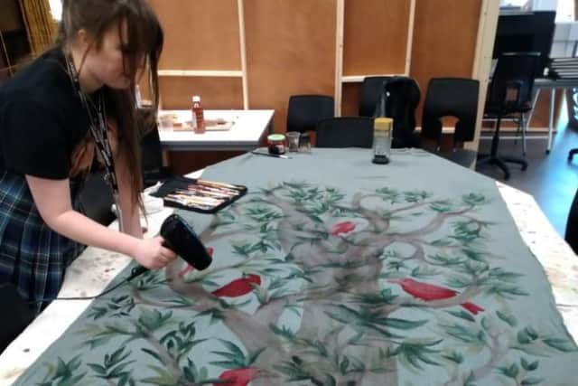 Northern School of Art student Amelia Mitchell painting a tapestry for the production.