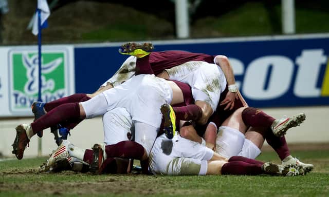 The Hearts players mob team mate Marius Zaliukas (hidden) after his goal secures the win for the away side