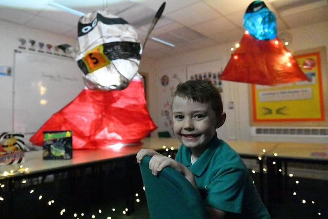 Jax Laverick sits in his classroom to admire the lanterns made by his fellow pupils.