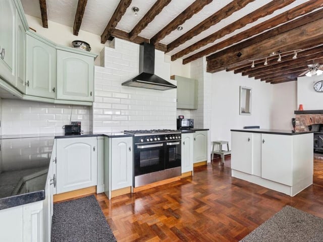 This large kitchen has a cast iron feature log burner, central island and French doors leading out into the conservatory extension.