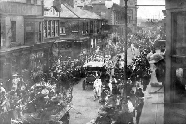 A parade passing through Lynn Street in the early 1900s with the sign for the 'Palace' in the distance.