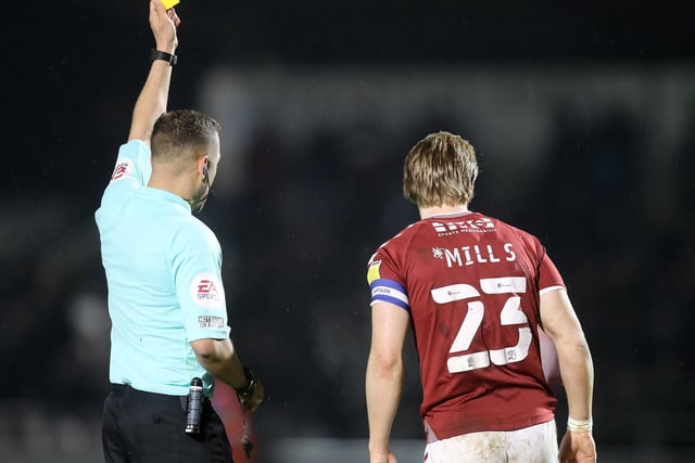 Joseph Mills of Northampton Town is shown a yellow card by  referee Paul Howard.