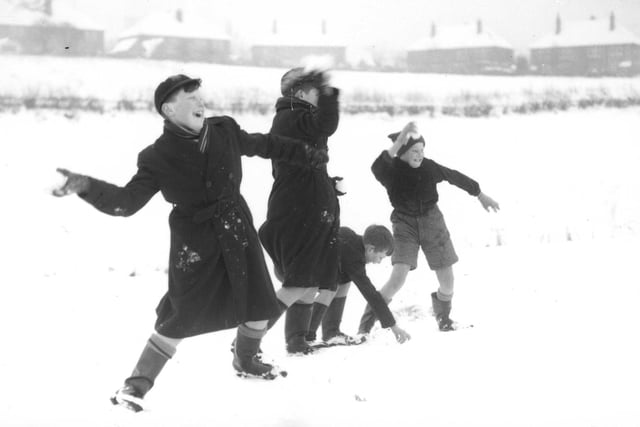Boys play in the snow in the back fields and start a snowball fight.