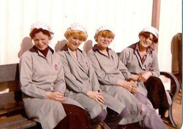 Four workers take a break in the sunshine outside their Brenda Road factory.