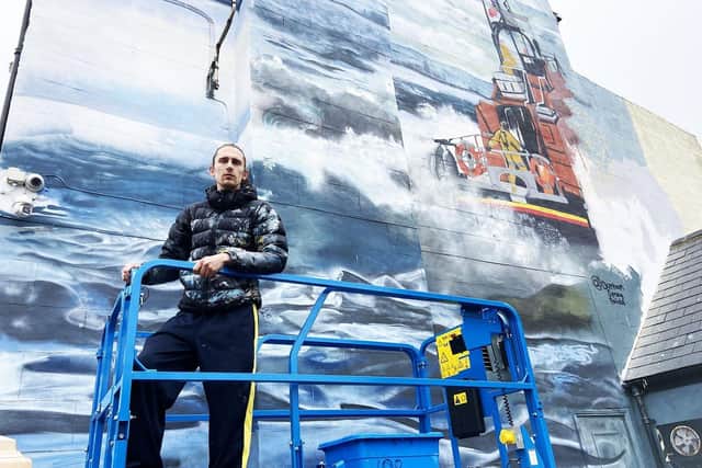 Artist Lewis Hobson with the RNLI lifeboat mural he painted on the side of The Ship Inn, in Middlegate, Hartlepool.