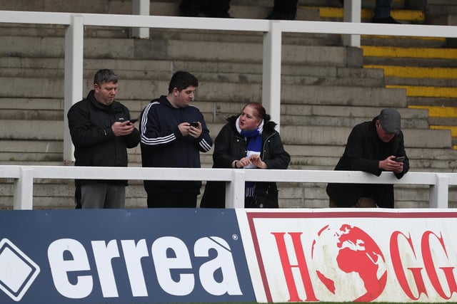 These fans are checking for live updates before the start of the match.