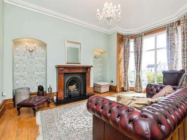 This reception room has exposed wooden floorboards and a bay window to the front.