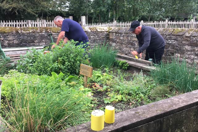 Visitors from the Men's Group tending to some of the plants in the cottage's garden.