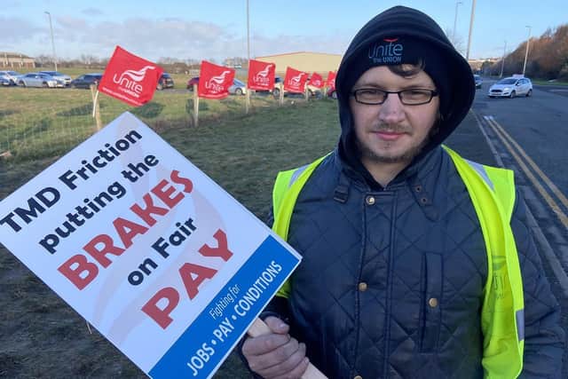 TMD Friction production operator Michael Noble with a placard.