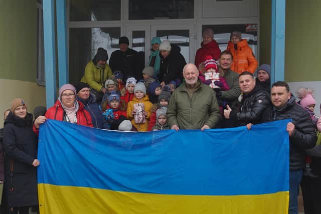 David Pond (right of centre) and Andy behind him to the right holding up a child, during a visit to children in the village of Muzykivka.