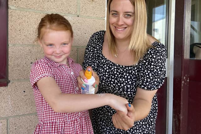 West View Primary School TA Melissa Wright sprays sun cream onto pupil Holly Moran.