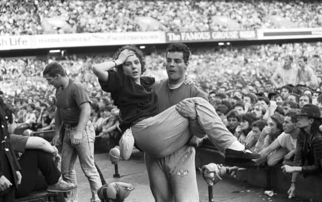 Stewards threw buckets of water to keep fans cool at the U2 concert at Murrayfield stadium Edinburgh, August 1987. This girl was overcome and had to be carried out.