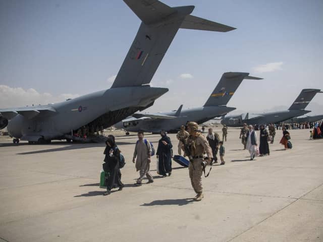 Soldiers escort refugees on to a waiting plane at Kabul Airport during the recent crisis.