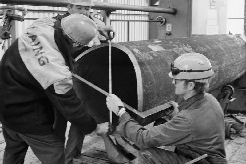 A team of Laing workers measuring a large metal tube in one of the welding huts at Graythorp in the early 1970's.