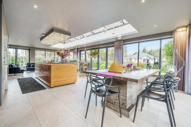 This home has a large, open plan kitchen and breakfast room featuring a roof lantern and full-height windows that wrap around the whole room, providing uninterrupted views across the garden. The kitchen also has a hidden caterer's kitchen that can be accessed through cupboard doors.
