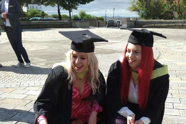 Two graduates share a laugh.