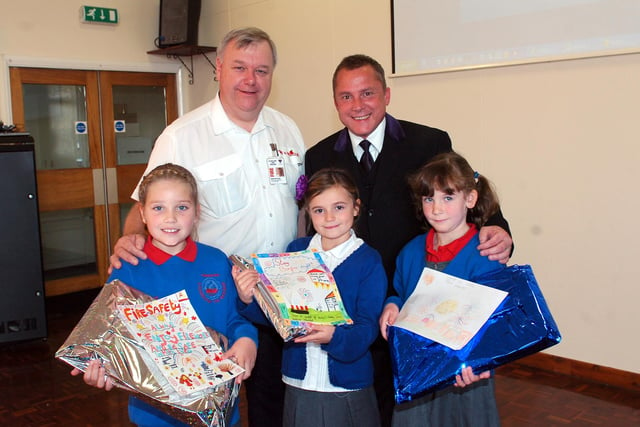 Derek Berryman (left), of Cleveland Fire Brigade, alongside Mark Evans, Co-op Funeral Care, who are presenting Throston Primary School pupils Eboney Paige Williams, Victoria Lynn and Emma Green with their fire safety design poster gifts.