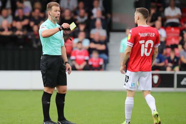 Referee Anthony Backhouse shows a yellow card to Ash Hunter of Salford City for simulation during the Sky Bet League Two match between Salford City and Northampton Town  at Peninsula Stadium on September 25, 2021 in Salford, England. (Photo by Pete Norton/Getty Images)
