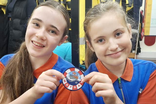 Alice Harper (left) and Mia Dale are pictured with one of the Mayday Mayday badges. Photo credit Tom Collins RNLI.