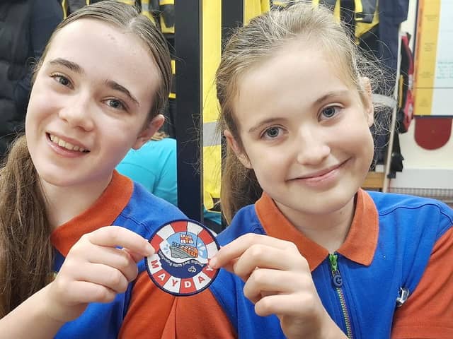 Alice Harper (left) and Mia Dale are pictured with one of the Mayday Mayday badges. Photo credit Tom Collins RNLI.