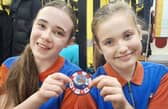 Alice Harper (left) and Mia Dale are pictured with one of the Mayday Mayday badges. Photo credit Tom Collins RNLI.