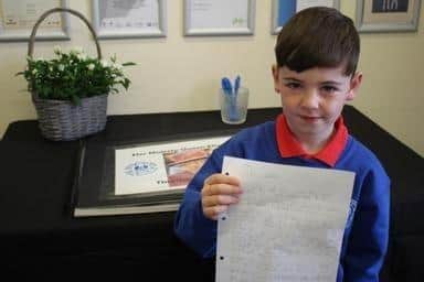 Henri Wood, 6, with the poem he wrote about Her Majesty Queen Elizabeth II, in Throston Primary School, next to their book of condolences.