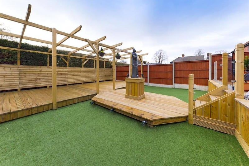 With areas of decking, artificial lawn and a water feature.