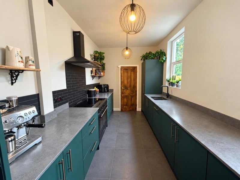 This galley kitchen has contrasting cabinets and worktops as well as a built-in coffee machine.