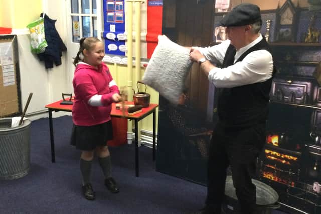 A pupil tries her hand at some old fashioned cleaning methods with local history volunteer Bill Elliott.