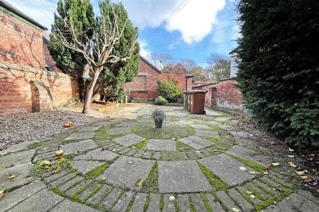 The rear garden boasts stone patios and mature trees.