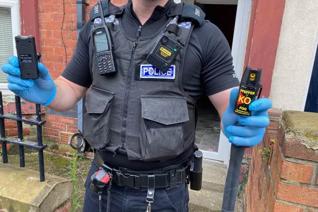 A police officer holds the taser (left), pepper spray and baton recovered from the house in Mitchell Street, Hartlepool.
