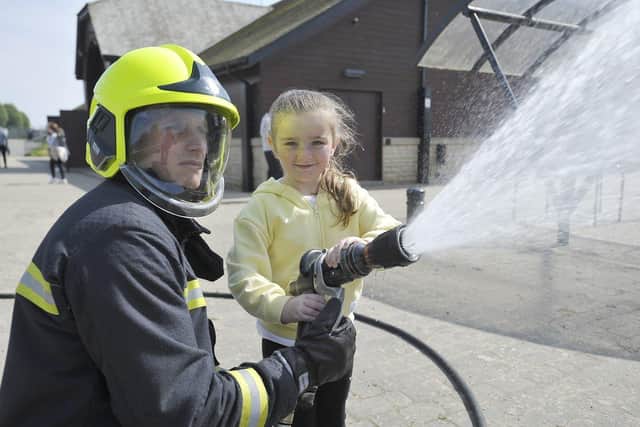 Firefighter Neil Farwell with Lady Watt (5) as she tries a fire hose at the Summerhill event. Picture by FRANK REID