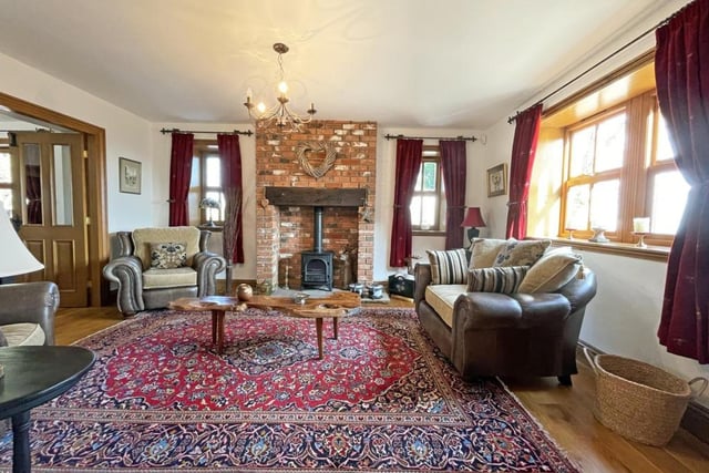 The main living room of the home features a brick fire place with log burner.