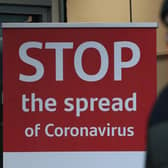 A man wearing a face mask walks past a coronavirus advice sign. Photo PA.