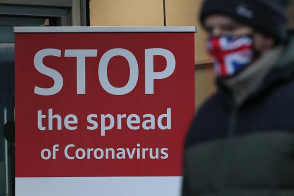 A man wearing a face mask walks past a coronavirus advice sign. Photo PA.
