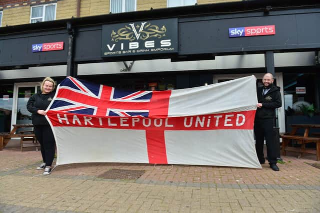 Leeroy Newsome, the general manager at Vibes sports bar, in Navigation Point, with bar manager Georgina Cooper with a giant Hartlepool United and England flag. Picture by FRANK REID.
